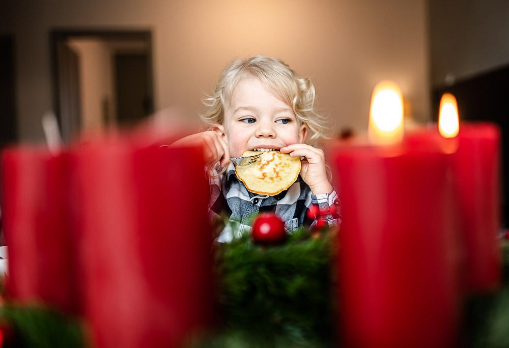Kind beißt in Pancake Weihnachtskranz im Vordergrund